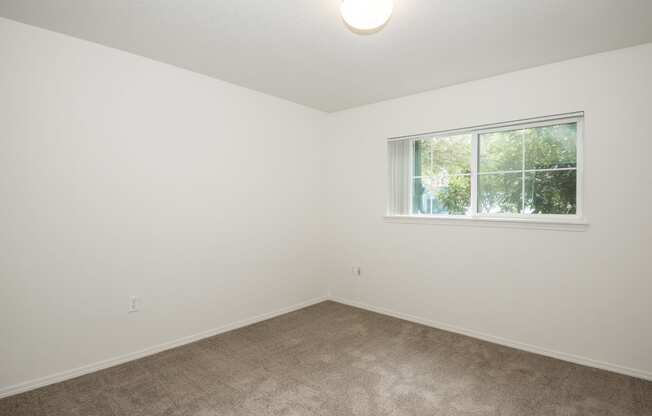 a bedroom with white walls and a window