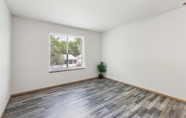 an empty room with wood floors and a window