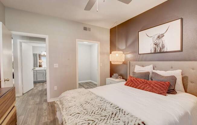 A bedroom with a large bed and a painting of a bull on the wall.