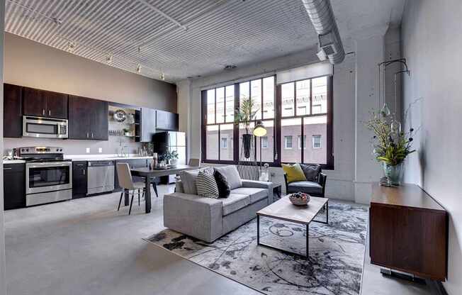 A modern open plan living and kitchen area with a grey sofa and a coffee table.