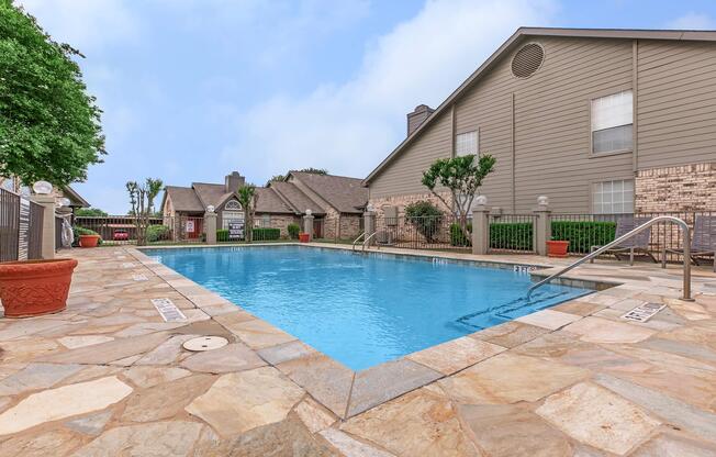 a house with a pool in front of a brick building