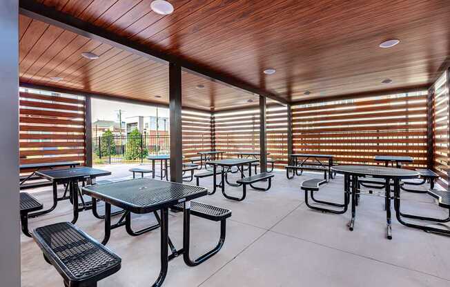 A patio with tables and chairs and a wooden ceiling.