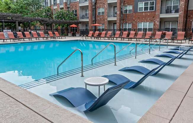 a swimming pool with chairs and a table in the middle
