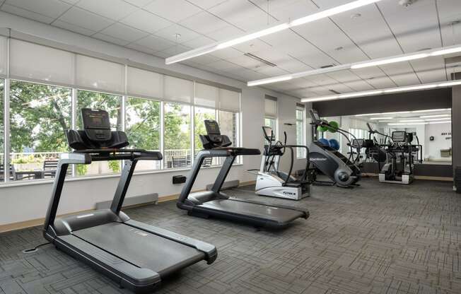 two treadmills and other exercise equipment in the fitness center of a building