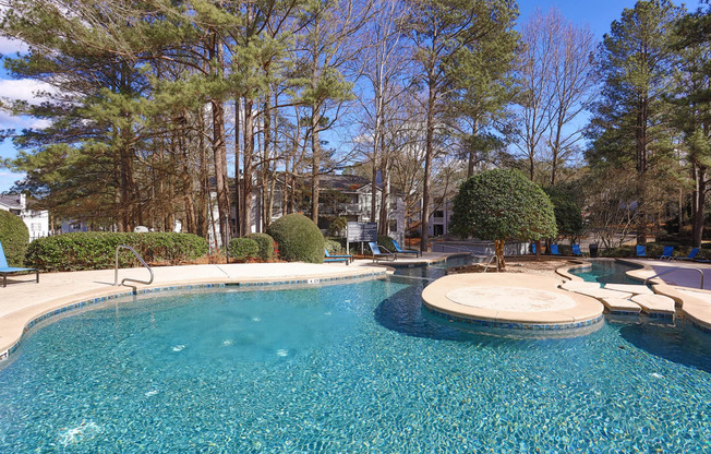 a swimming pool with a patio and trees in the background