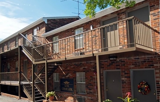 an exterior view of a brick apartment building with a wooden balcony