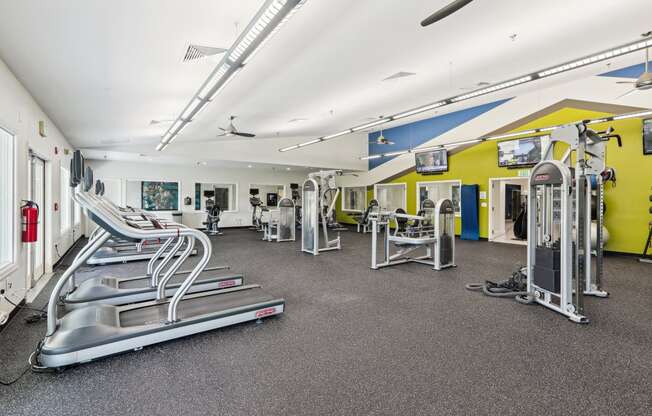 a gym with cardio equipment and weights on the floor