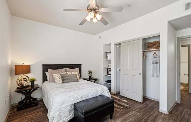 A bedroom with a bed, nightstand, and a ceiling fan.