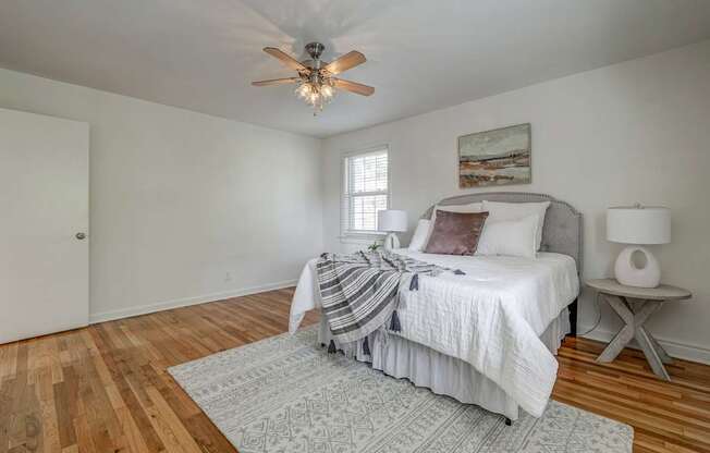 A bedroom with a bed, a ceiling fan, and a rug.