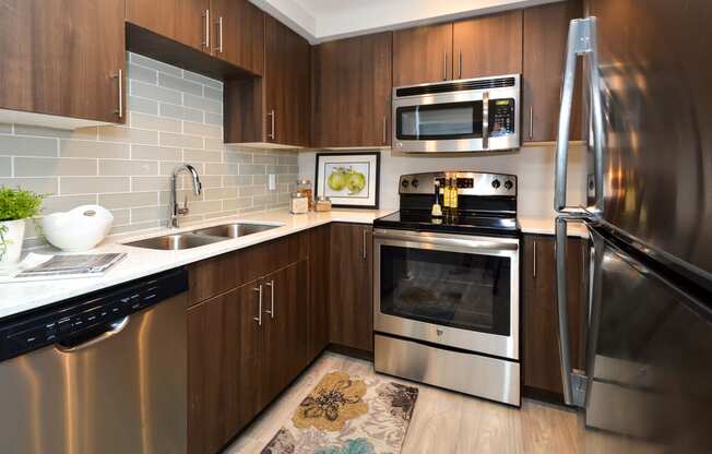a kitchen with stainless steel appliances and wooden cabinets at Apartments at Denver Place, Denver, 80202