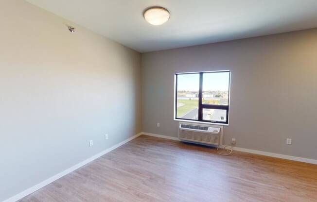 an empty living room with a window and wood floors