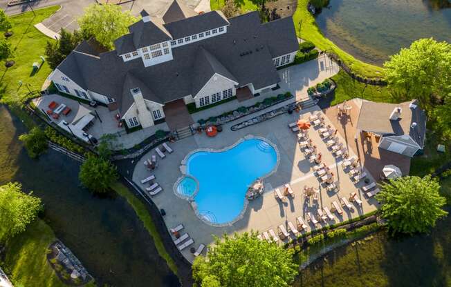 an aerial view of a resort style swimming pool in front of a large house with