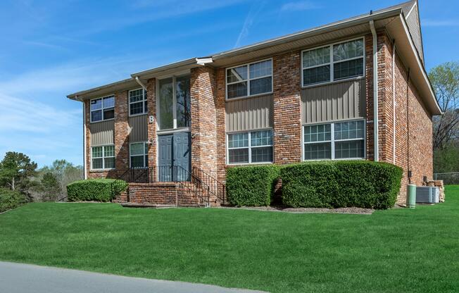 a house with a lawn in front of a brick building