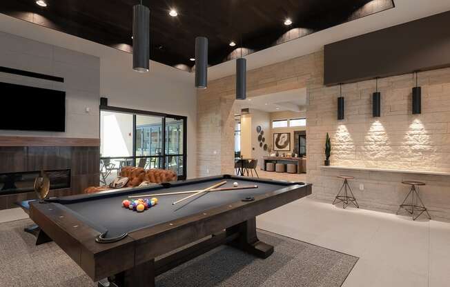 A pool table is in the middle of a room with a fireplace and a TV.