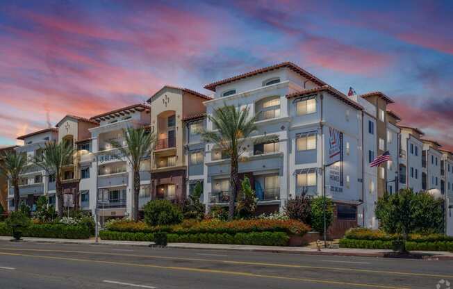 an apartment building on the corner of a street at sunset