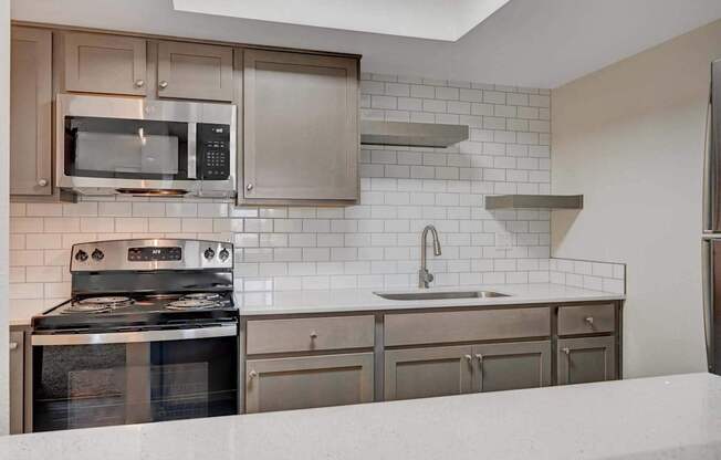 A modern kitchen with stainless steel appliances and white subway tiles.