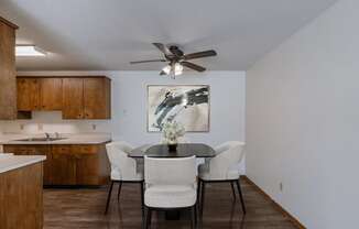 a dining room with a table and chairs and a ceiling fan. Fargo, ND Windsor Apartments