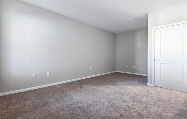A room with a carpeted floor and a white door.