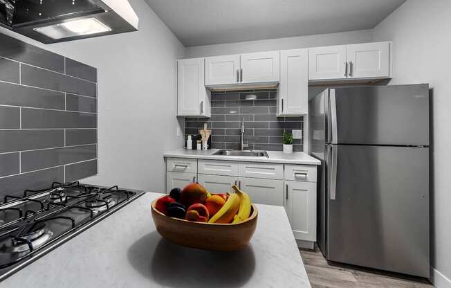 A modern kitchen with a bowl of fruit on the counter.