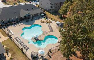 A large outdoor swimming pool surrounded by a fence and lounge chairs.
