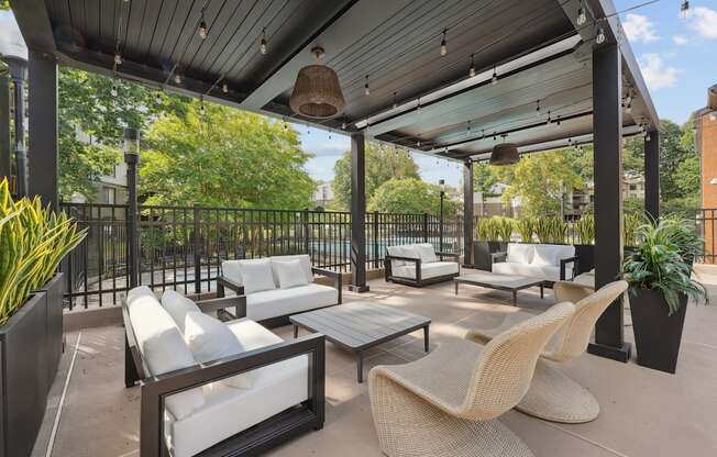 A patio with white cushioned furniture and a black metal fence.