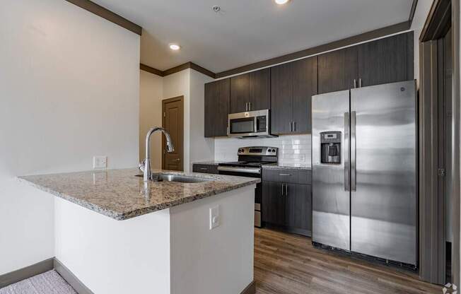 A kitchen with a granite countertop and stainless steel appliances.