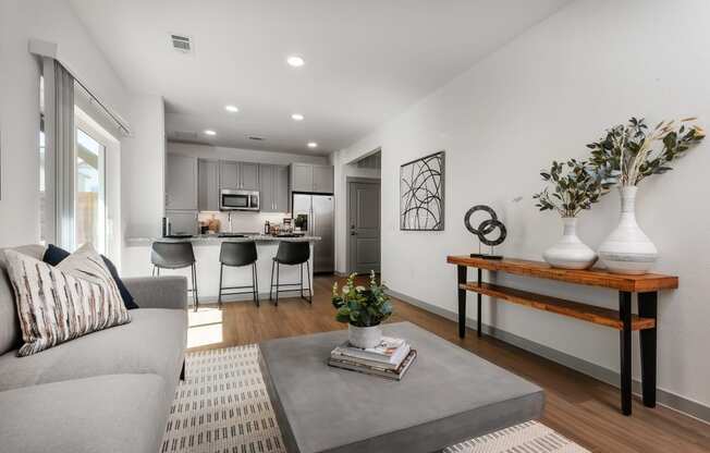 a living room with a couch and a coffee table in front of a kitchen