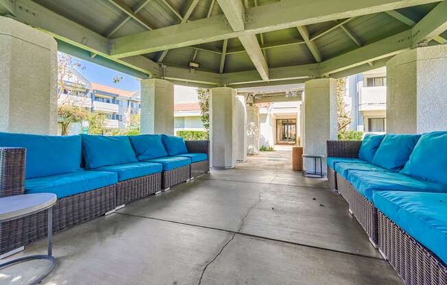 a covered patio with blue couches and tables