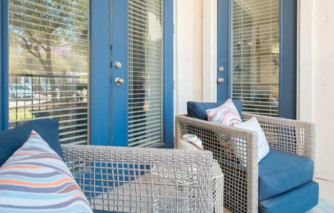 A blue chair with a pillow and a striped cushion is in front of a window.