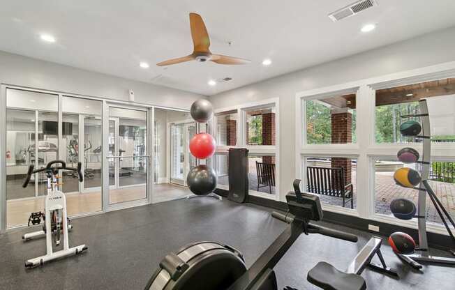 A gym with a variety of equipment including a stationary bike, a rowing machine, and a bench press.