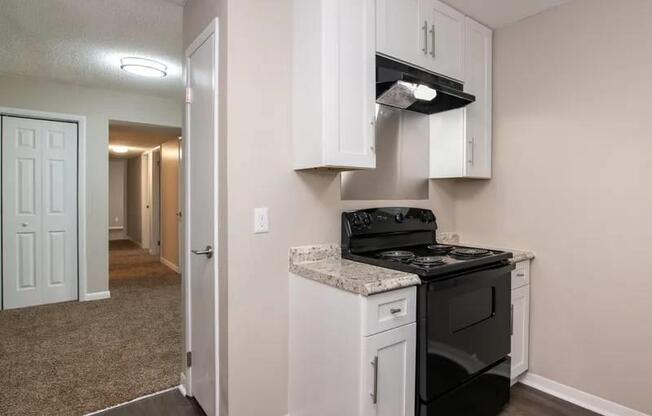 a kitchen with white cabinets and a black stove at Cleo Apartments, Athens, 35611