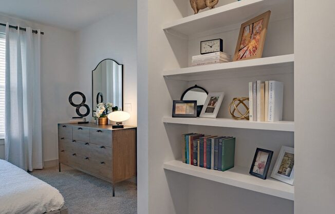a bedroom with white shelves and a bed and a dresser