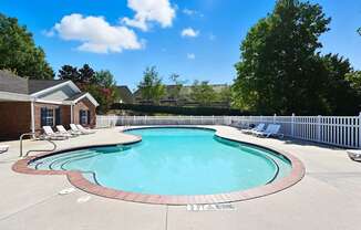 A small pool with a brick border and a white fence.