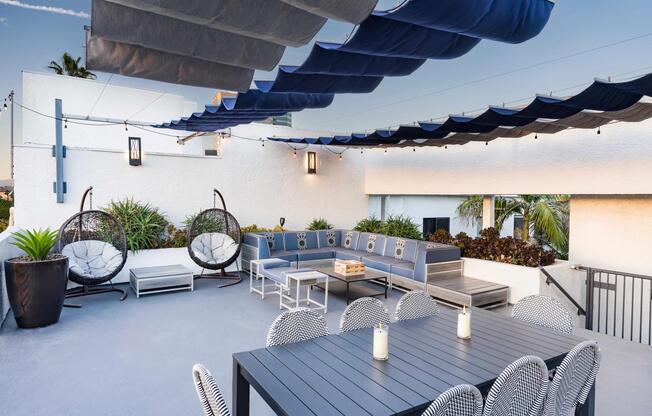 Lounge in the open air with shaded seating, dining area, and cozy gathering spaces under string lights.