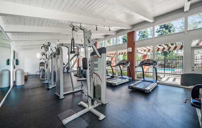 A gym with a variety of equipment including treadmills, weights, and exercise machines.