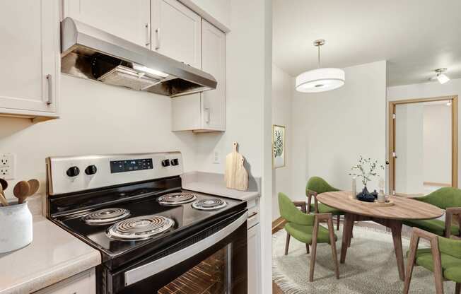 a kitchen with a stove and a dining room with a table and chairs