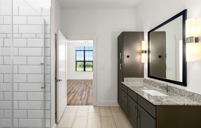 A bathroom with a white tiled shower area and a marble counter top.