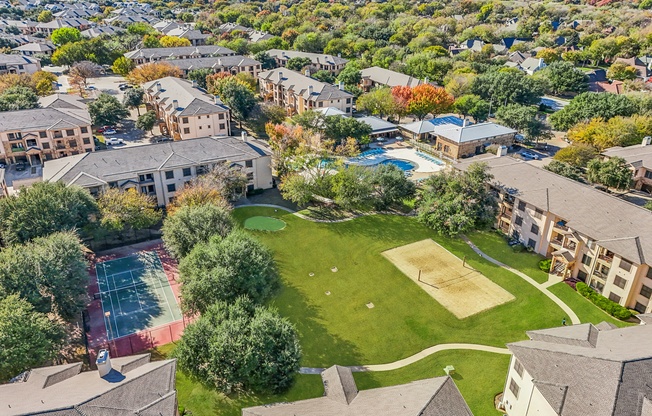 A bird's eye view of a residential area with a tennis court and a basketball court.