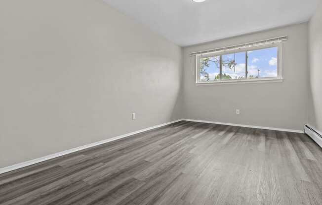 an empty bedroom with wood floors and a window
