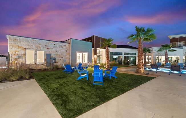 A modern building with a stone wall and palm trees in front.
