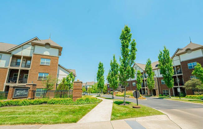 a street view of an apartment complex with trees and a sidewalk