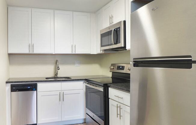 an empty kitchen with white cabinets and stainless steel appliances at The Packard, Connecticut, 06119