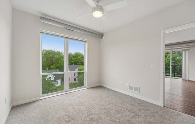 A room with a ceiling fan and sliding glass doors.