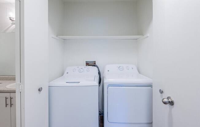 Two white front loading washing machines in a small laundry room.