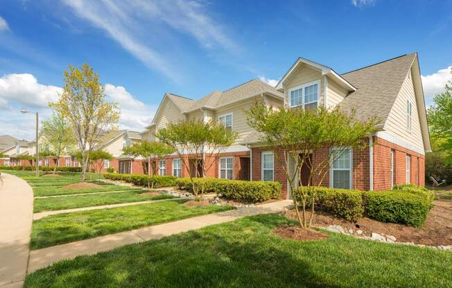 A row of houses with green lawns and trees in front at Haven at Research Triangle Park apartments in Durham, NC.