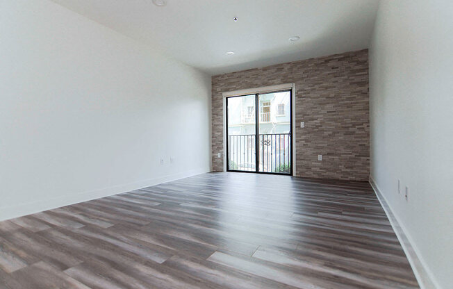 Living room with stone accent wall and view of balcony.