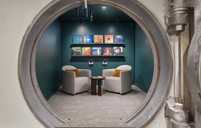 A room with a circular opening in the wall and two chairs.