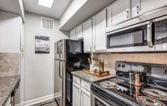 an updated kitchen with stainless steel appliances and white cabinets