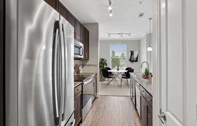 A modern kitchen with a stainless steel refrigerator and wooden flooring.