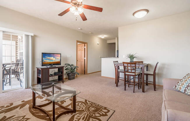 a living room and dining room with a table and a ceiling fan